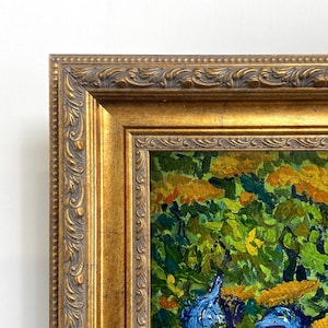 Könnte beinhalten: Gerahmtes Gemälde mit einer lebendigen Blumenszene. Das Kunstwerk zeigt einen üppigen Garten mit blauen Schwertlilien, gelben Blumen und grünem Laub. Das Gemälde ist in einem goldfarbenen, verzierten Rahmen eingefasst.