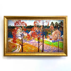 May include: A framed landscape painting with a gold-coloured frame. The artwork depicts a colourful autumn scene with trees in shades of red and orange, a winding path, and a village in the background. The painting is set against a white background.