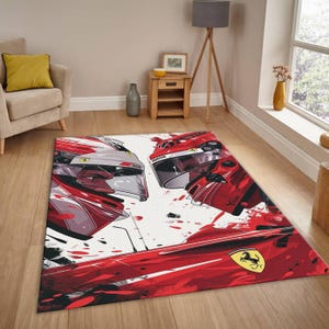 May include: A rectangular area rug featuring a graphic design of two racing helmets in red, white, and gray. The rug has a white background with red paint splatter effects and the Ferrari logo.
