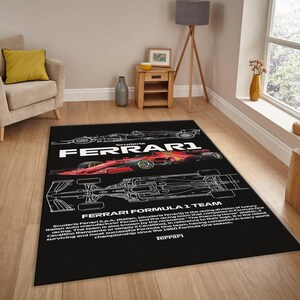 May include: Black rectangular rug featuring a red and black Ferrari Formula 1 race car design. The rug has the word "FERRARI" in large white letters, along with text describing the team's history. The rug is placed on a wooden floor.