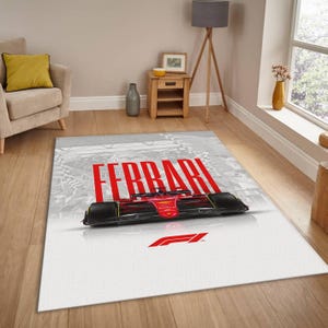 May include: A rectangular area rug featuring a red Ferrari Formula 1 race car design. The rug has a white background with the word "FERRARI" in large red letters. The Formula 1 logo is also visible in red.