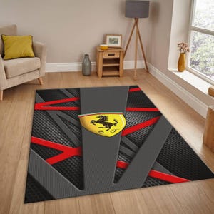 May include: A rectangular area rug with a gray and black textured design, accented with red lines. The rug features the Ferrari logo in the center, a yellow shield with a black horse.