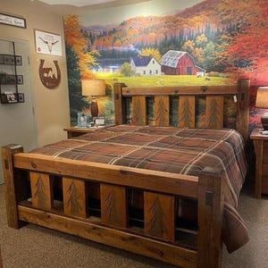 May include: A rustic wooden bed frame with a headboard and footboard. The headboard and footboard feature carved tree designs. The bed is covered with a plaid comforter. The room has a mural of a landscape scene.