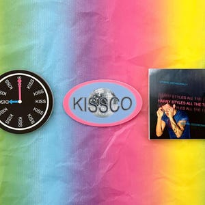 May include: A collection of stickers featuring a disco ball, a clock with "Disco Kiss" text, and a square sticker with the text "Harry Styles All The Time". The stickers are on a rainbow-colored background.