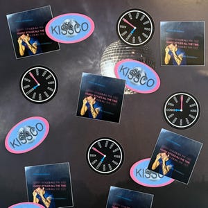 May include: A collection of stickers and magnets featuring a disco ball, clock designs, and images of a person. The stickers have the text "KISSCO" and "HARRY STYLES ALL THE TIME". The clock designs have the word "KISS" and "DISCO".