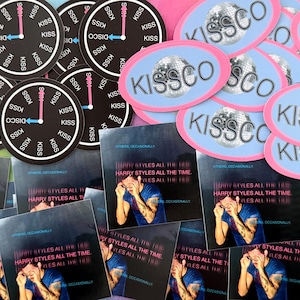 May include: A selection of stickers and album art. The stickers display the text "KISSCO" and a disco ball design, and clock faces with the word "KISS." The album art features the text "HARRY STYLES ALL THE TIME."