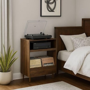 May include: A wooden record player stand with a turntable, amplifier, and record storage. The stand is next to a bed with white bedding and a framed abstract art piece. A potted plant and rug are also in the room.