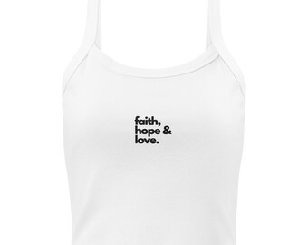 May include: White crop top with thin straps and the words "faith, hope & love" in black, centered on the front. The top has a rounded neckline and a simple, minimalist design.