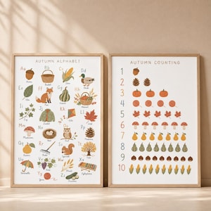May include: Two educational wall posters in light wood frames. The left poster, titled Autumn Alphabet, features letters A through Z with corresponding autumn-themed illustrations. The right poster, titled Autumn Counting, displays numbers 1 through 10.