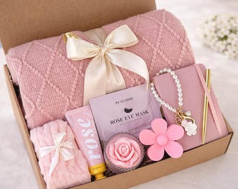 May include: A gift box labeled "BlissBox" filled with a pink blanket, a notebook, a bracelet, a flower-shaped item, a rose-scented product, and a rose-shaped soap. The box is labeled "Blush Harmony Box".