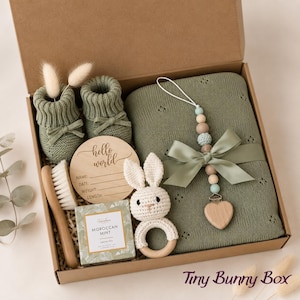 Curated newborn baby gift box with soft neutral and sage details, cozy baby essentials, bunny-inspired keepsakes, and thoughtful gifts for new parents. A beautiful baby shower gift basket, welcome baby gift box, new baby gift basket, new mom gift box, mom and baby gift, postpartum gift basket, and gender neutral baby gift for a newborn baby boy or girl.