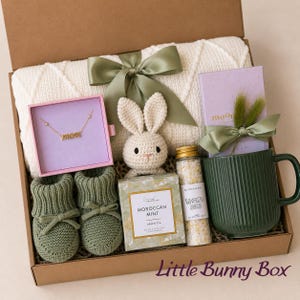 Curated newborn baby gift box with soft neutral and sage details, cozy baby essentials, bunny-inspired keepsakes, and thoughtful gifts for new parents. A beautiful baby shower gift basket, welcome baby gift box, new baby gift basket, new mom gift box, mom and baby gift, postpartum gift basket, and gender neutral baby gift for a newborn baby boy or girl.