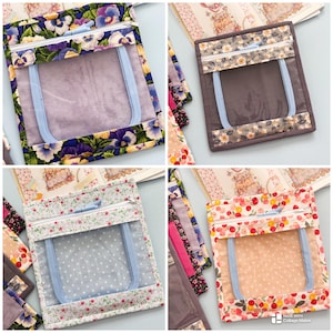 Può includere: Una collezione di quattro pochette quadrate in tessuto, ciascuna dotata di una finestra in vinile trasparente e una cerniera azzurra. Le pochette sono decorate con vari motivi floreali in viola, grigio, bianco e pesca con chiusura superiore.