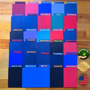 May include: A collection of thirty rectangular plastic file dividers in various shades of blue, red, and pink, each featuring a raised team name label including D'Backs, Reds, Dodgers, Yankees, Mariners, Braves, Guardians, Angels, A's, Cardinals, Orioles, Rockies, Marlins, Phillies, Rays, Red Sox, Tigers, Brewers, Pirates, Rangers, Cubs, Astros, Twins, Padres, Blue Jays, White Sox, Royals, Mets, Giants, and Nationals.