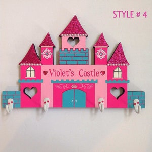 K&ouml;nnte beinhalten: Rosa und t&uuml;rkisfarbener, schlosf&ouml;rmiger Schl&uuml;sselhalter aus Holz mit den Worten "Violet's Castle" und vier Haken. STYLE #4 steht oben rechts.