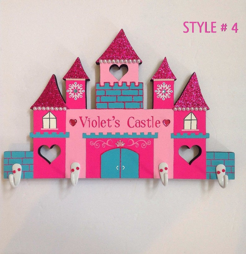 K&ouml;nnte beinhalten: Rosa und t&uuml;rkisfarbener, schlosf&ouml;rmiger Schl&uuml;sselhalter aus Holz mit den Worten "Violet's Castle" und vier Haken. STYLE #4 steht oben rechts.