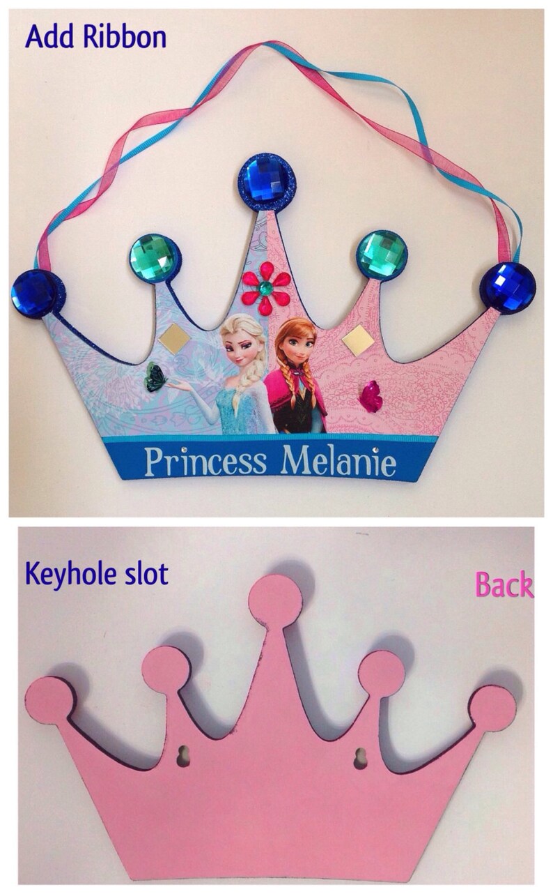 K&ouml;nnte beinhalten: Rosa Holz-Prinzessinnenkrone mit einem Schl&uuml;sselloch auf der R&uuml;ckseite. Die Vorderseite der Krone ist mit einem blauen und rosa Band, einem Bild von Elsa und Anna aus Frozen und den Worten "Princess Melanie" verziert.