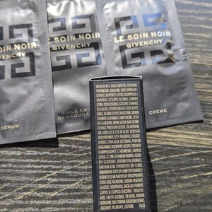 Op de afbeelding: Zwarte zakjes en een kleine zwarte doos met witte tekst. De zakjes zijn gelabeld met "Le Soin Noir Givenchy". De doos bevat een lijst met ingredi&euml;nten. De zakjes zijn voor huidverzorgingsproducten.
