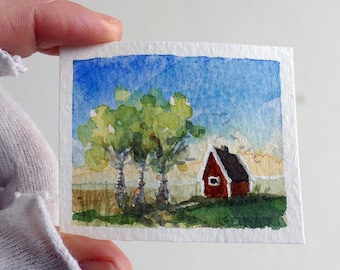 Swedish countryside landscape. Original miniature watercolor painting. Blue sky, red house, green tree. Aquarelle art by artist Ilse Hviid