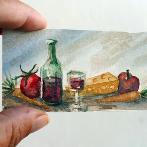 Puede incluir: Acuarela de un bodegón con una botella de vino verde, una copa de vino tinto, un tomate rojo, un trozo de queso, una manzana y zanahorias. El estilo es rústico y artístico.