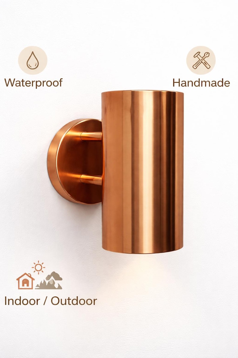 May include: A copper-colored cylindrical wall sconce with a circular base and two small support arms. The sconce is labeled "Waterproof", "Handmade", and "Indoor / Outdoor".