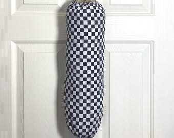 May include: A fabric bag with a black and white checkered pattern, hanging from a white hook on a white door. The bag has a drawstring closure at the top and a loop for hanging.