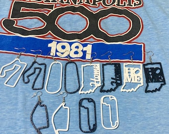May include: A collection of dangling earrings featuring various shapes, including outlines of the state of Indiana, race tracks, and the word Home. The earrings are rendered in solid white and dark blue glitter finishes, each equipped with silver-toned hooks.