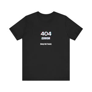 Può includere: T-shirt nero con la scritta "404 ERROR Sleep Not Found." Il testo ha un effetto glitch. La maglietta è a maniche corte e girocollo.