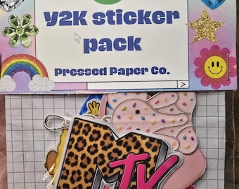 May include: A Y2K sticker pack with a variety of designs, including a leopard print MTV logo, a rainbow, and a smiling flower. The pack is packaged in a clear plastic sleeve with a grid-patterned backing.