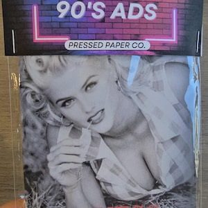 May include: A package featuring a black and white image of a woman from a Guess ad. The package has the text "ICONIC 90'S ADS" in white and pink neon against a brick background. The word "GUESS" is in red.