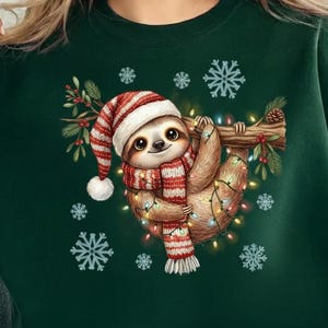 May include: A dark green sweatshirt featuring a festive sloth design. The sloth, adorned with a Santa hat and scarf, hangs from a branch decorated with lights and snowflakes. A cozy and seasonal apparel item.