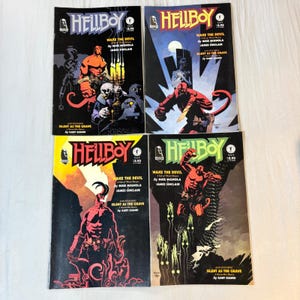 May include: Four Hellboy comic books from the Wake the Devil series, issues 2 through 5. Each cover features the red-skinned character Hellboy in various action poses with bold titles, creator credits, and dark, atmospheric graphic illustrations.