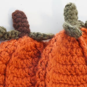 Close-up of the crochet pumpkin hat pattern texture, showing the ribbed body with green leaf and stem details