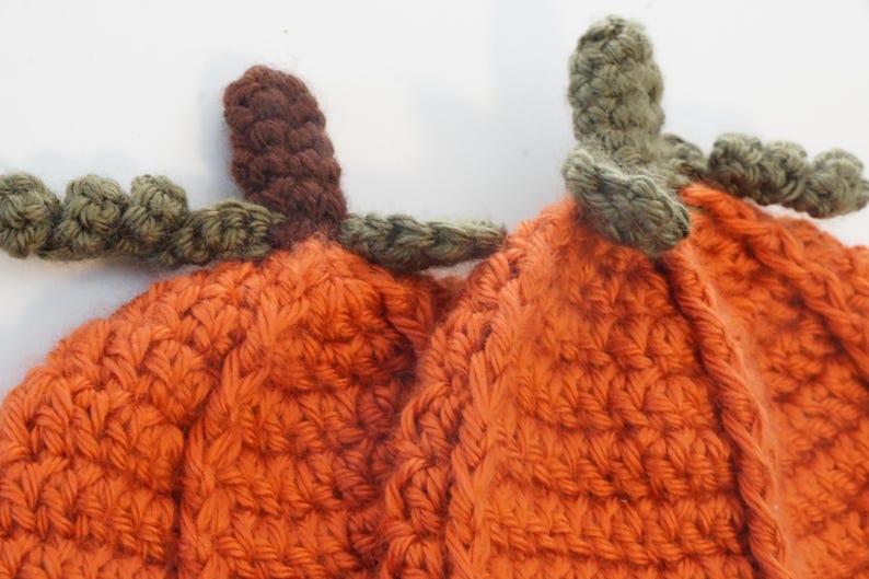 Close-up of the crochet pumpkin hat pattern texture, showing the ribbed body with green leaf and stem details