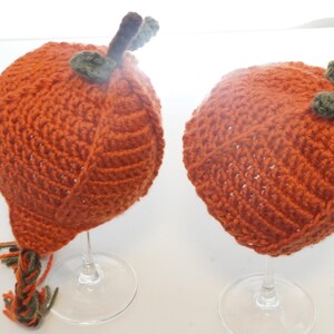 Side view of two pumpkin hat pattern samples on glass stands, highlighting the spiral ribbing and stem toppers