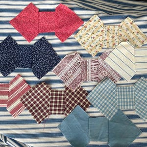 May include: A collection of ten fabric quilt blocks arranged in a grid. Each block features a central rectangular piece flanked by two diamond-shaped side panels. The fabrics include various patterns such as red floral, blue vine, yellow floral, striped, plaid, and solid blue cotton prints.