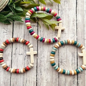 May include: Three colorful beaded bracelets with white cross charms. Each bracelet features a different color scheme, including teal, red, brown, and white.