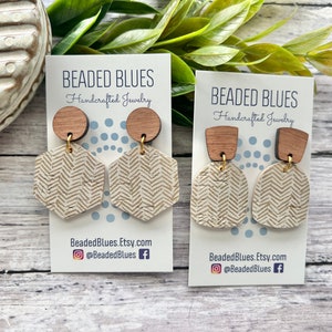 May include: Two pairs of handmade earrings with a chevron pattern. The earrings are made of wood and have a gold-tone metal hook. The earrings are displayed on a white card with the text "BEADED BLUES Handcrafted Jewelry" and the website address "BeadedBlues.Etsy.com".
