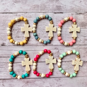 May include: Six colorful beaded bracelets with white cross charms. The bracelets are made with different colored beads, including yellow, blue, pink, turquoise, and green.
