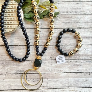 Black animal print cheetah wood bead necklace. Gold circle pendant. Long black wood beaded necklace.