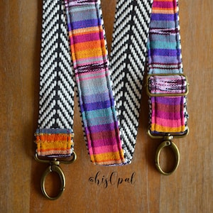 May include: A black and white chevron patterned strap with a colourful striped accent. The strap has two gold metal clasps.