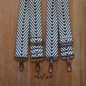 May include: Two black and white chevron patterned straps with gold and silver metal hardware. The straps have a herringbone pattern and are adjustable.