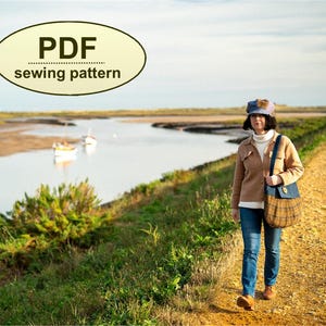 K&ouml;nnte beinhalten: Eine Person in einer beigen Jacke, blauen Jeans und einer karierten Handtasche geht einen Feldweg entlang neben einem Gew&auml;sser. Das Bild enth&auml;lt den Text "PDF sewing pattern" in einem gelben Oval.
