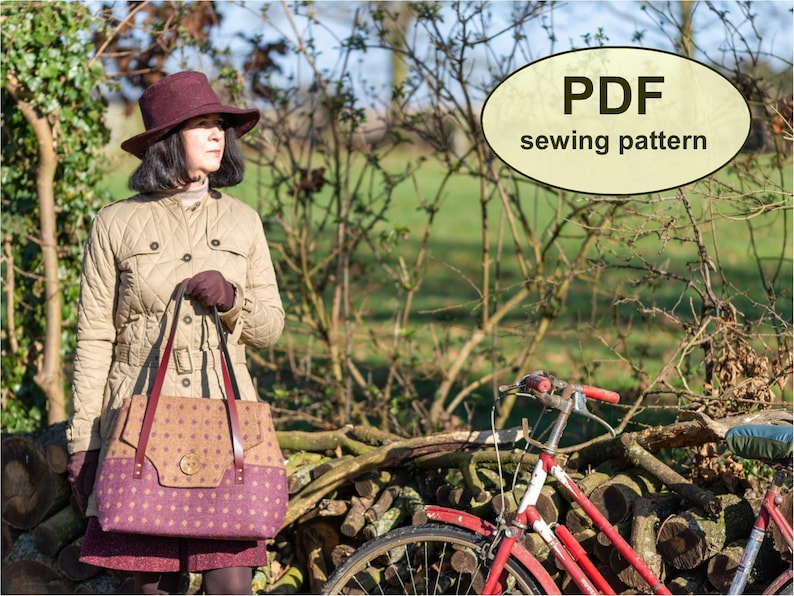 May include: A woman wearing a brown quilted jacket and a burgundy hat is holding a brown and purple tote bag with a large button detail. The bag has a brown leather strap. The woman is standing in front of a pile of logs and a red bicycle.