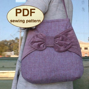 Può includere: Una borsa tote in tessuto viola con un grande fiocco di velluto sul davanti. La borsa ha una tracolla lunga ed è tenuta da una persona. Il testo "PDF sewing pattern" è su un adesivo ovale beige.