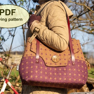 May include: A PDF sewing pattern for a brown and purple tweed tote bag with a leather strap and a large wooden button. The bag is being held by a person wearing a brown jacket.