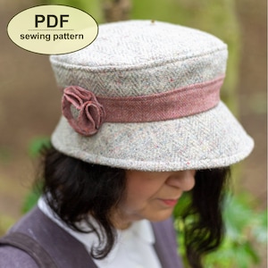 May include: A PDF sewing pattern for a gray and pink tweed cloche hat with a pink ribbon and a pink flower accent.