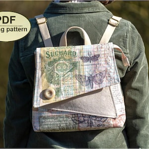 May include: A vintage-style backpack in beige and multi-coloured tones, adorned with butterfly illustrations and text. The bag has adjustable straps and a top handle. The word "SUCHARD" is printed on the front. A button secures the flap closure.