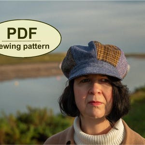 May include: A woman wearing a patchwork newsboy cap with blue, brown, and purple fabric. The cap is part of a PDF sewing pattern, as indicated by the text in the image. The background features a body of water and a cloudy sky.