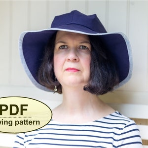 May include: A woman wearing a navy blue sun hat with a white trim and a striped shirt. The hat is a PDF sewing pattern.